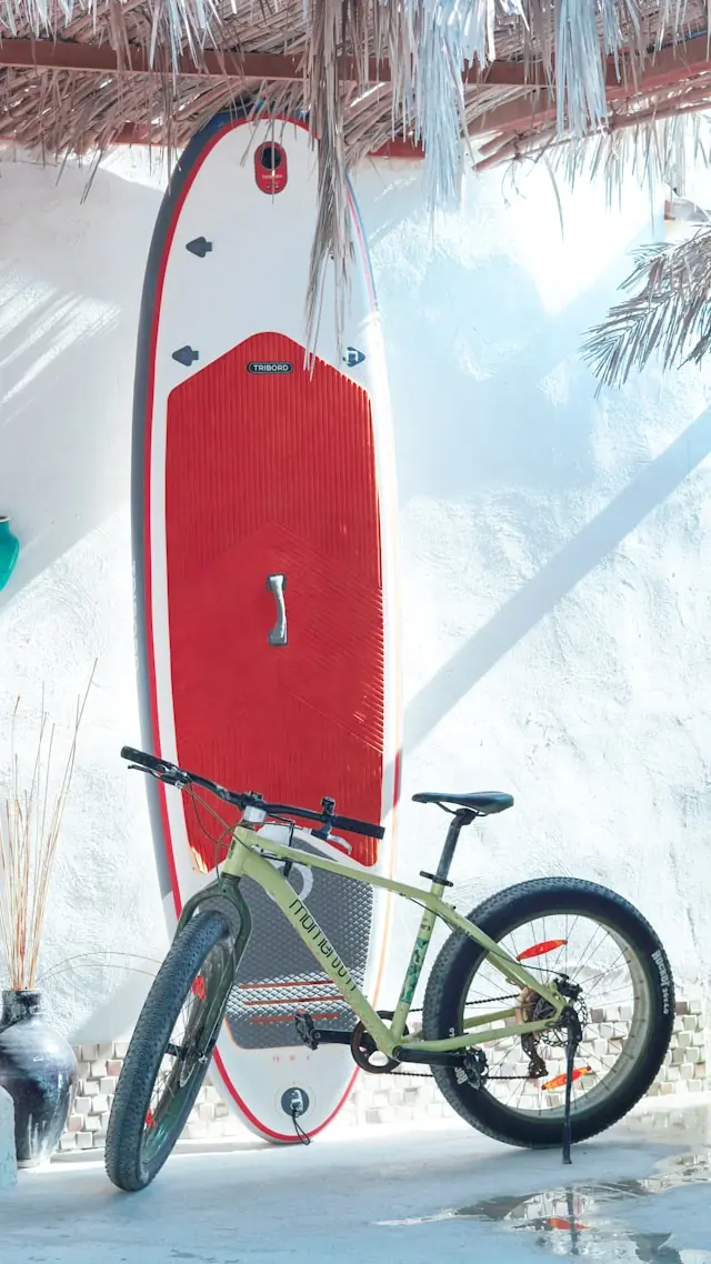 Bicycle parked near a surfboard in a tropical setting in Hawaiʻi