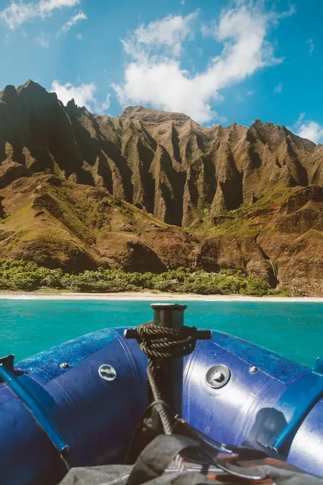 View from a boat along the coastline in Hawaiʻi with mountains in the background