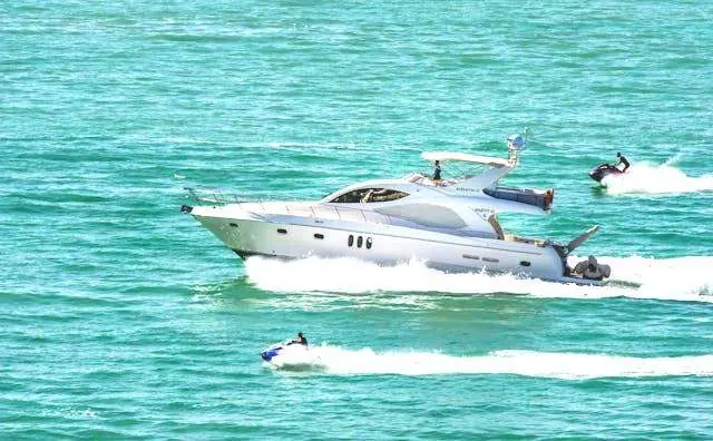 Boat and multiple jet skis traveling close together on the ocean