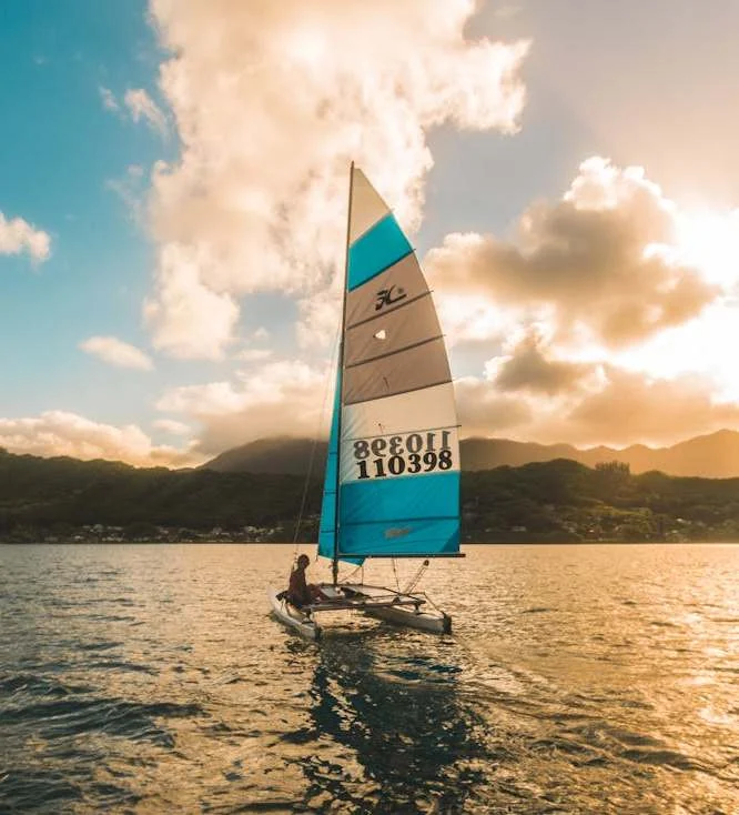Catamaran sailing on the ocean in Hawaiʻi during sunset