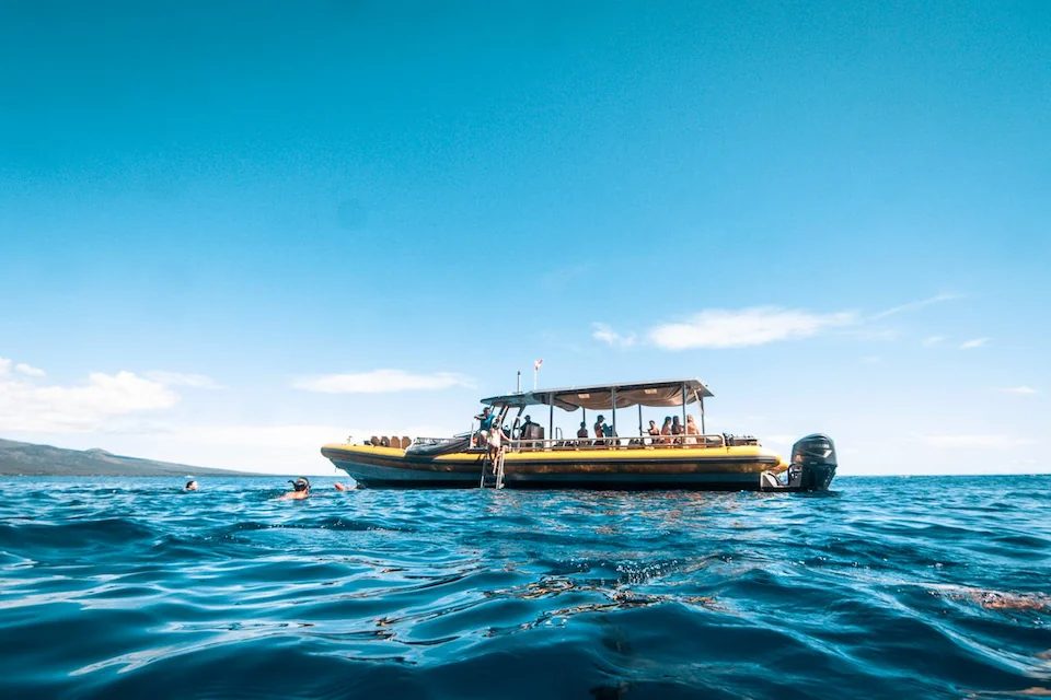 Tour boat with passengers on the ocean in Hawaiʻi with people swimming nearby