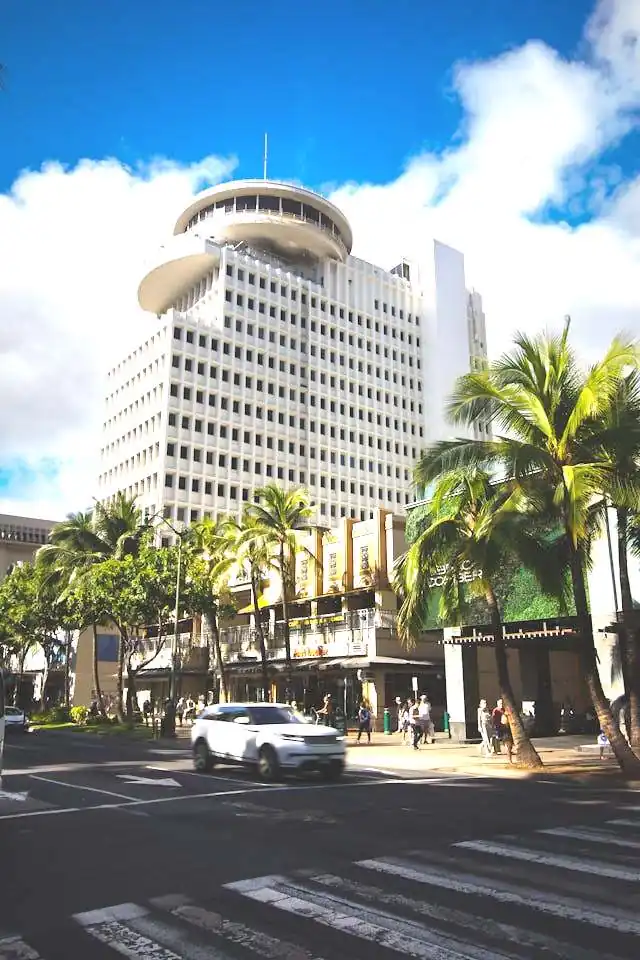 Urban street in Honolulu, Hawaiʻi, with crosswalk, traffic, and pedestrians near high-rise buildings