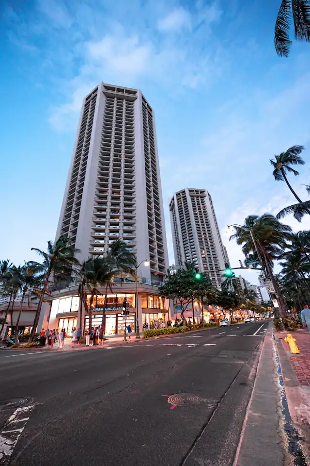 Urban street intersection in Honolulu with traffic lights, pedestrians, and high-rise buildings