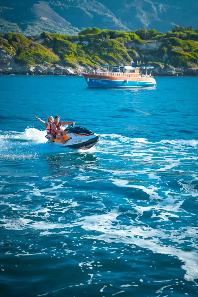 Two people riding a jet ski on the ocean near a boat in Hawaiʻi