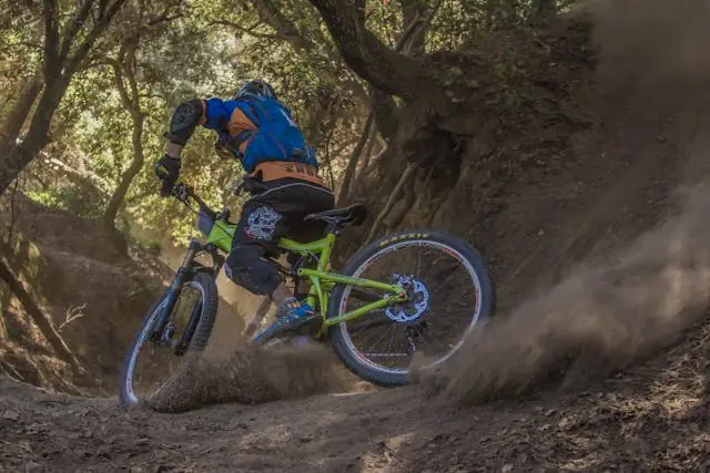 Mountain biker riding on a dirt trail, kicking up dust while navigating a turn