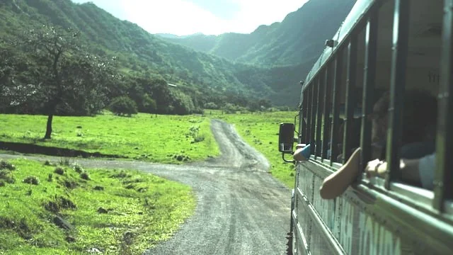 View from a tour bus driving on a rural road through a green landscape in Hawaiʻi