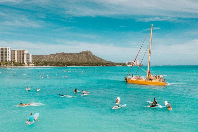 Boat near swimmers and surfers in the ocean at Waikīkī Beach in Honolulu with Diamond Head in the background