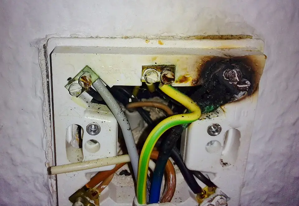 Burned electrical wiring inside a wall outlet illustrating a dangerous product or installation defect