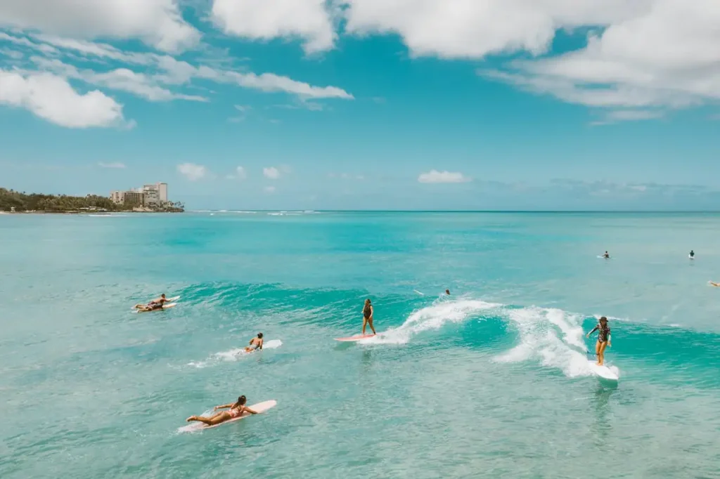 Several surfers riding and paddling for small waves in Waikīkī, Hawaiʻi, while sharing the lineup and monitoring ocean conditions.